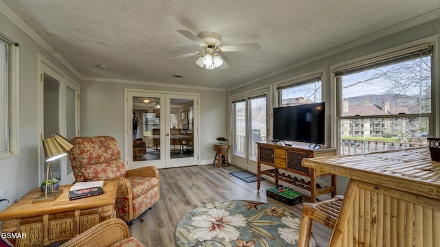 interior space with a textured ceiling, crown molding, wood finished floors, and a ceiling fan