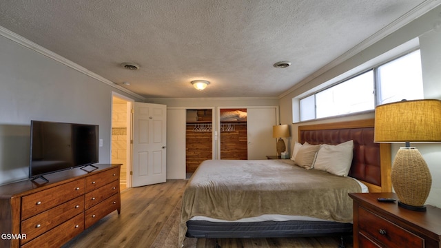 bedroom with visible vents, a textured ceiling, wood finished floors, and crown molding