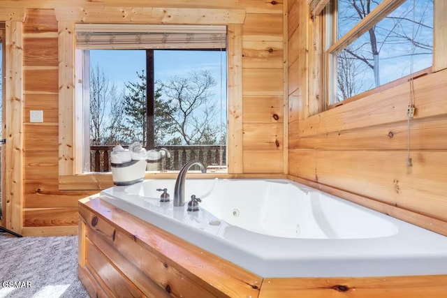bathroom featuring a tub with jets and wooden walls