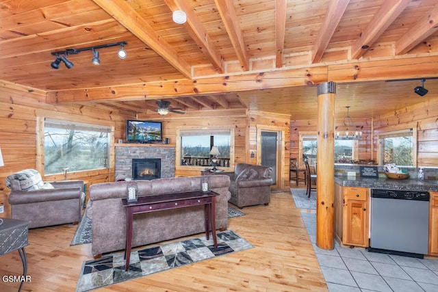 living room featuring track lighting, beamed ceiling, and wooden walls