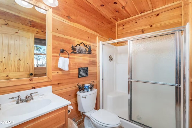 bathroom with toilet, wooden walls, vanity, and a stall shower