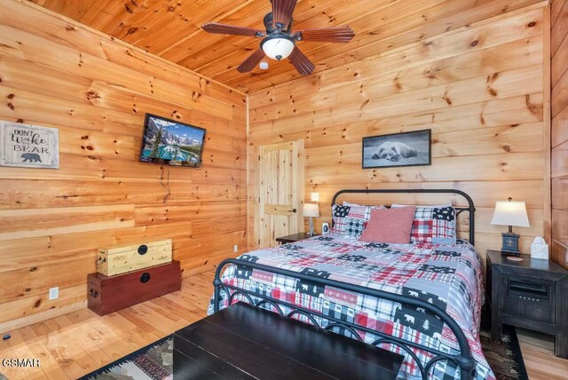 bedroom with wood finished floors, a ceiling fan, wooden walls, and wood ceiling