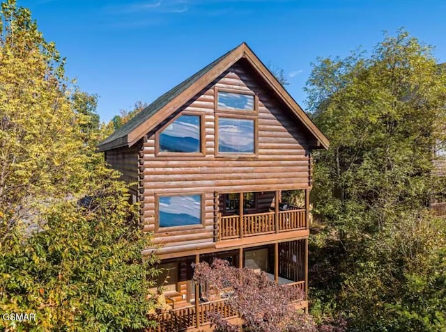 rear view of property featuring a balcony and log siding
