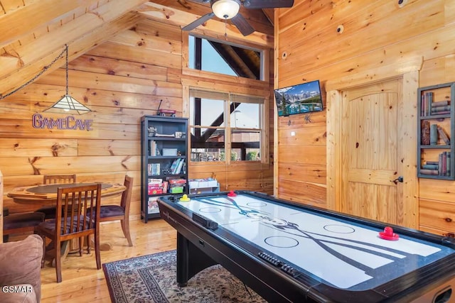 game room featuring wood walls, lofted ceiling with beams, and ceiling fan