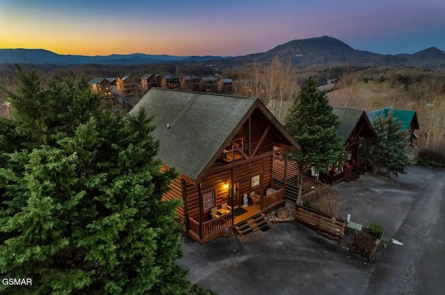 exterior space with roof with shingles, a mountain view, and log veneer siding