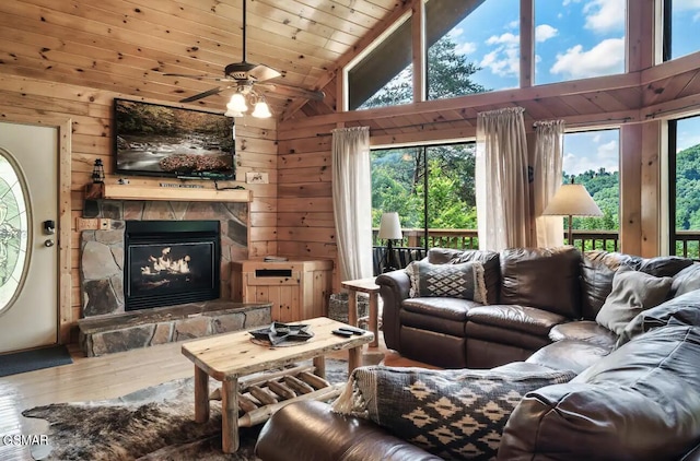 living room with hardwood / wood-style flooring, high vaulted ceiling, wooden walls, and a stone fireplace