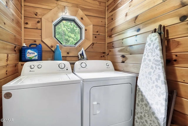 washroom with washing machine and clothes dryer and wooden walls