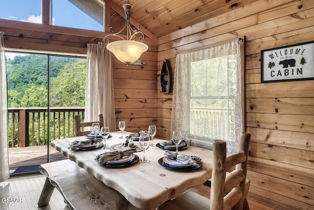 dining space with hardwood / wood-style flooring, wooden walls, wood ceiling, and vaulted ceiling