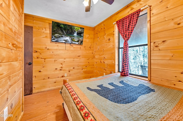 unfurnished bedroom with wood walls, ceiling fan, and wood finished floors