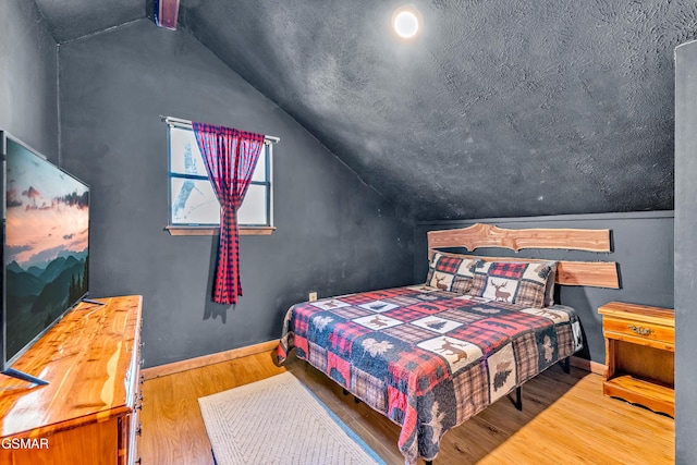 bedroom featuring lofted ceiling, baseboards, and wood finished floors