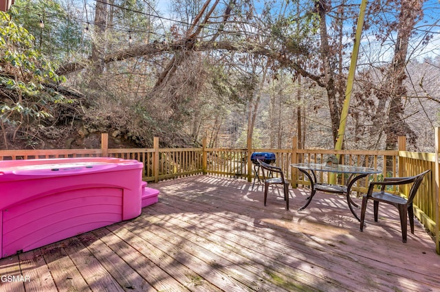 wooden deck with outdoor dining space and a hot tub