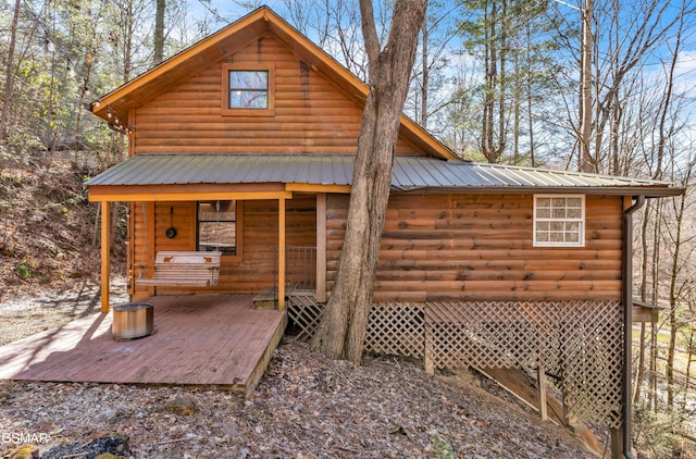 back of house with faux log siding and metal roof