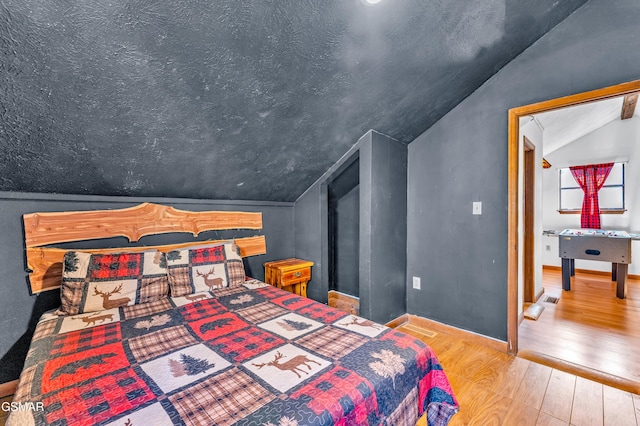 bedroom featuring vaulted ceiling, baseboards, and wood finished floors