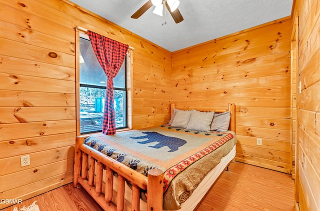 bedroom featuring ceiling fan, wood walls, and wood finished floors