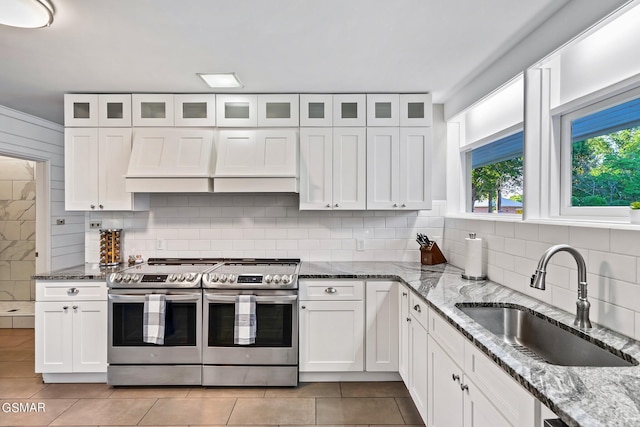 kitchen with decorative backsplash, light stone countertops, sink, double oven range, and white cabinets