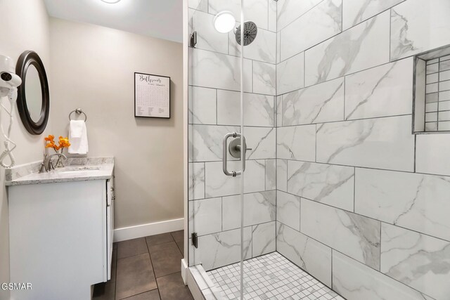 bathroom with a shower with door, vanity, and tile patterned flooring