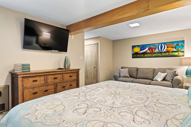 bedroom featuring beamed ceiling and a closet