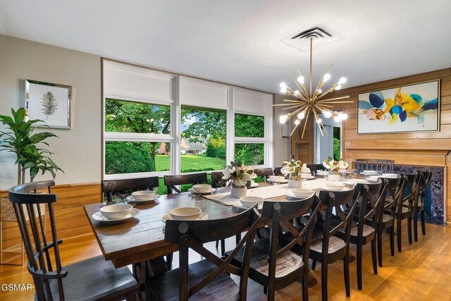 dining room with wooden walls, a chandelier, and hardwood / wood-style flooring