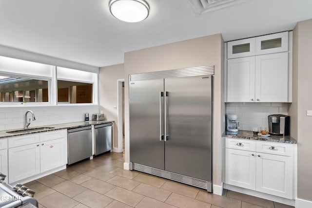 kitchen featuring white cabinetry, sink, tasteful backsplash, dark stone counters, and appliances with stainless steel finishes