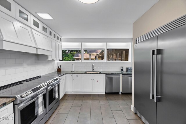 kitchen featuring sink, light tile patterned floors, decorative backsplash, white cabinets, and appliances with stainless steel finishes