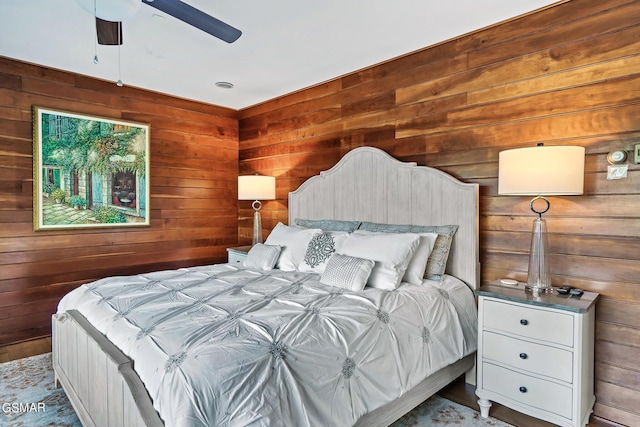 bedroom featuring ceiling fan and wooden walls