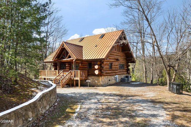 cabin featuring central air condition unit, a standing seam roof, metal roof, log siding, and driveway