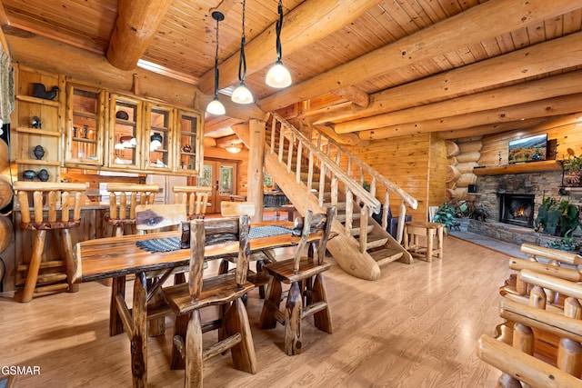 dining area with beam ceiling, a fireplace, stairway, light wood-style floors, and wooden ceiling