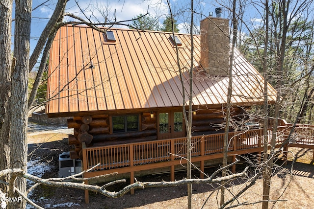 rear view of property with a chimney, log siding, metal roof, and a gambrel roof