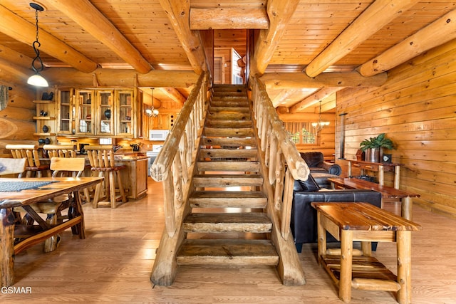 stairway with an inviting chandelier, wood ceiling, log walls, and wood finished floors