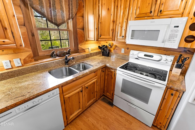 kitchen featuring light wood-style floors, white appliances, brown cabinets, and a sink