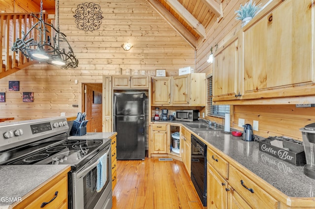 kitchen with wooden walls, black appliances, light wood-type flooring, and a sink