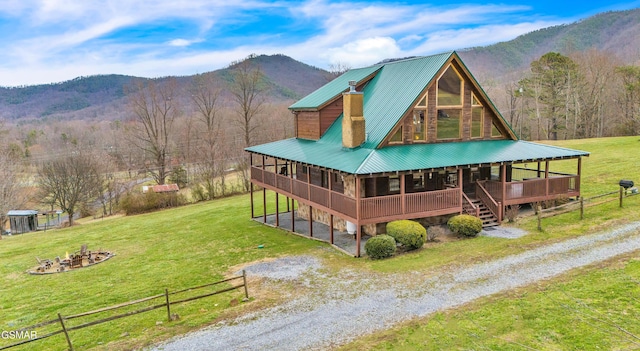 exterior space with a yard, a mountain view, driveway, and an outdoor fire pit