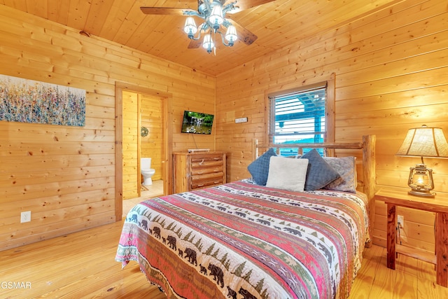 bedroom with ceiling fan, wood walls, wooden ceiling, ensuite bathroom, and light wood-style floors