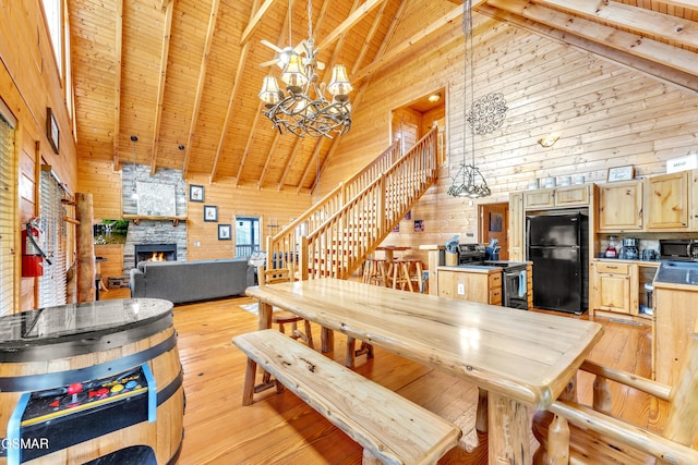 dining room featuring a stone fireplace, wood ceiling, light wood-style floors, wood walls, and a chandelier