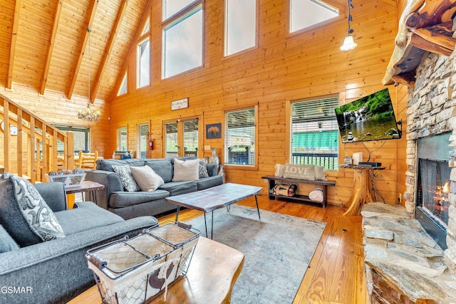 living area featuring stairway, wood walls, a stone fireplace, wooden ceiling, and wood-type flooring