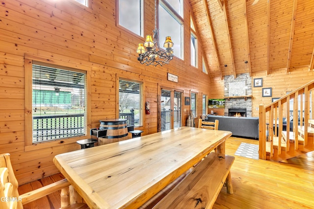 dining room with wooden walls, a stone fireplace, stairs, and wood finished floors