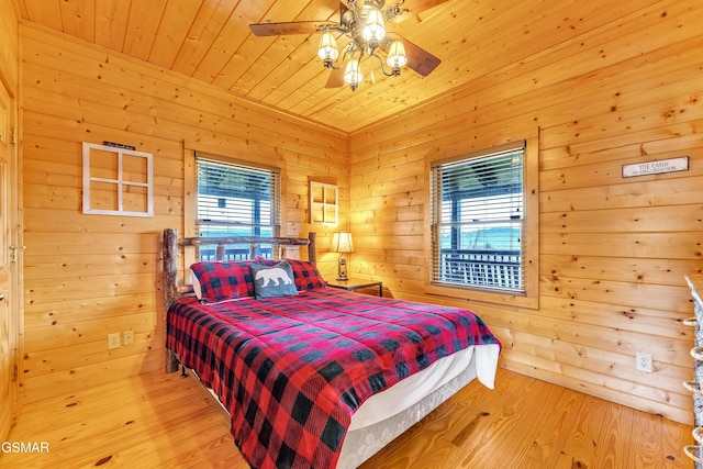 bedroom featuring ceiling fan, wooden walls, wood ceiling, and light wood-style flooring