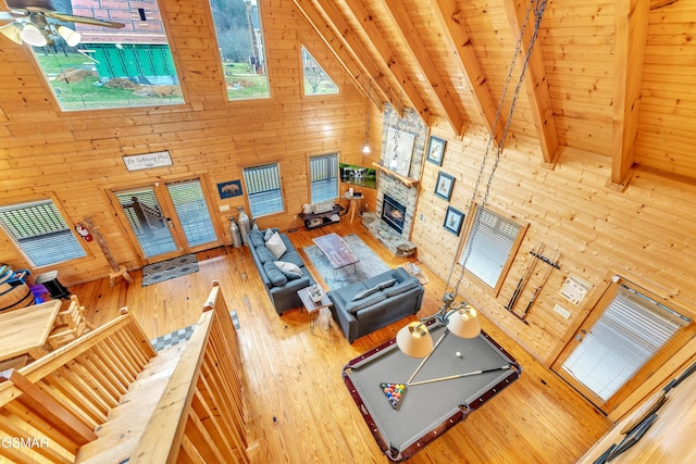 living room with beam ceiling, wood walls, a fireplace, and high vaulted ceiling