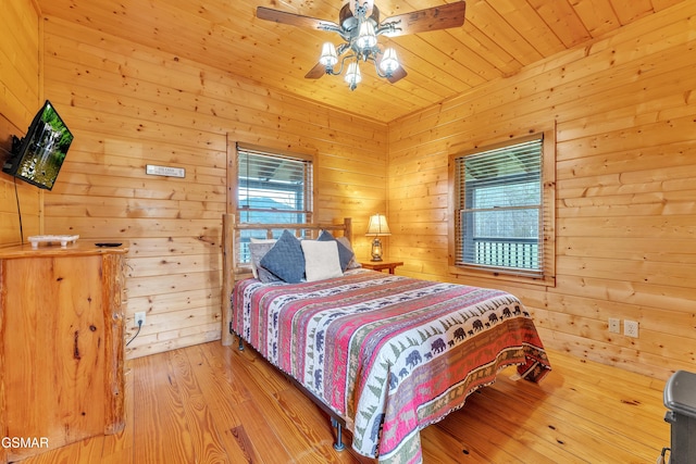 bedroom featuring multiple windows, wood finished floors, wooden walls, and wooden ceiling