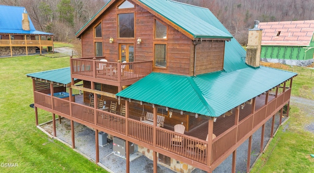 rear view of property featuring metal roof, a lawn, and a wooden deck