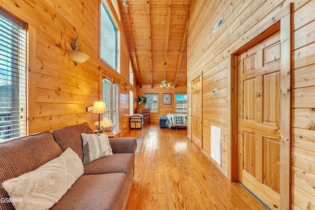 unfurnished living room featuring visible vents, high vaulted ceiling, light wood-style flooring, wood walls, and wooden ceiling