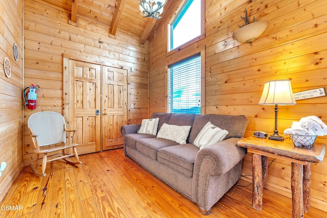 living area with beamed ceiling, wood walls, wooden ceiling, wood finished floors, and high vaulted ceiling