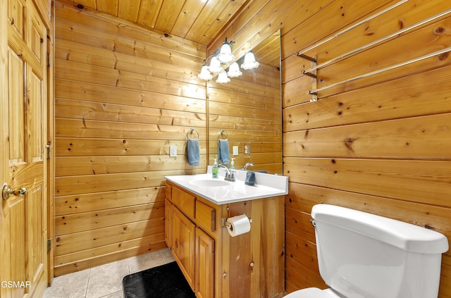 bathroom with toilet, wooden walls, tile patterned flooring, wood ceiling, and vanity