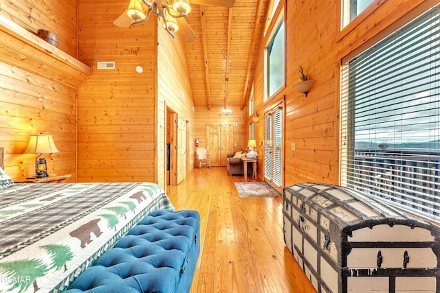 bedroom with visible vents, wood walls, a high ceiling, and wood-type flooring