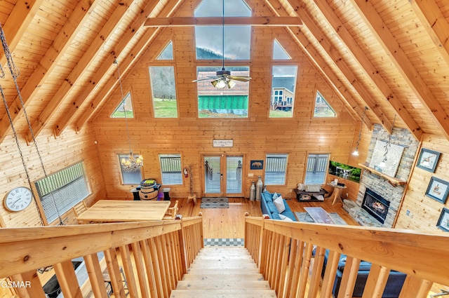 interior space with beam ceiling, wooden walls, a stone fireplace, and wooden ceiling