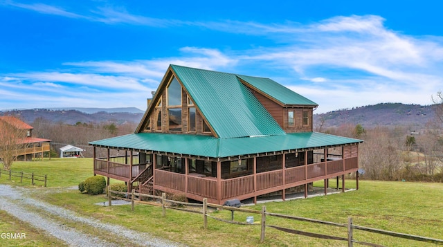 exterior space featuring a mountain view, metal roof, driveway, and a yard