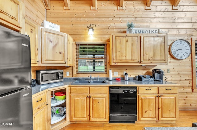 kitchen featuring wooden walls, light brown cabinetry, light wood-type flooring, black appliances, and a sink