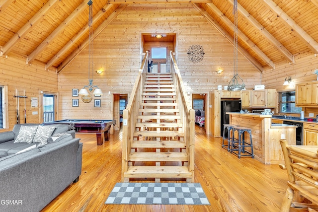 living room with billiards, stairway, light wood-style flooring, and beamed ceiling