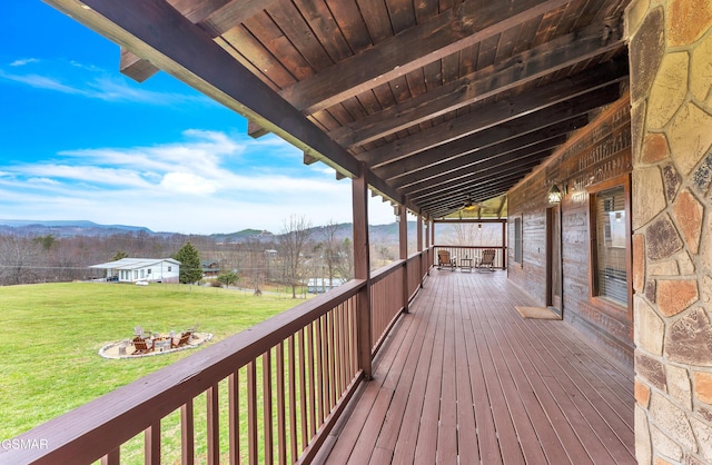 wooden terrace featuring a lawn, a mountain view, and an outdoor fire pit