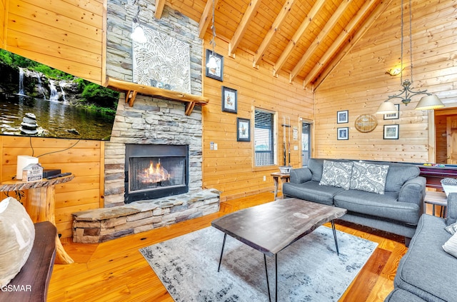 living room featuring beam ceiling, wood finished floors, a stone fireplace, wooden ceiling, and wood walls